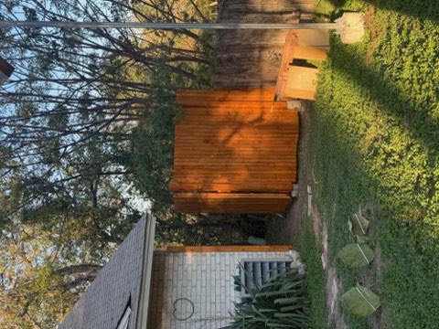 Wooden fence, grassy yard, brick house, and trees in an outdoor residential area.
