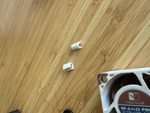 Two white plastic connectors and a Noctua NF-A4x20 PWM fan on a bamboo surface.